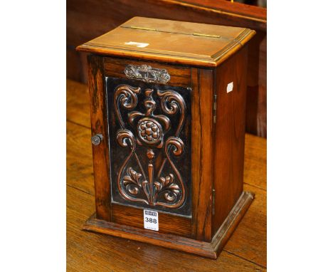 An Art Nouveau oak smokers cabinet, with hinged door decorated with copper embossed stylized panel, enclosing fitted drawer a