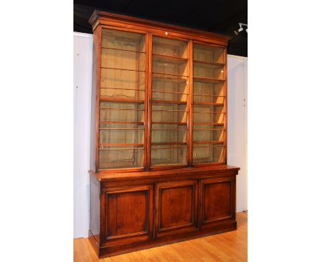 A large Victorian mahogany library bookcase, with moulded cornice above three glazed doors, enclosing fitted shelves above th