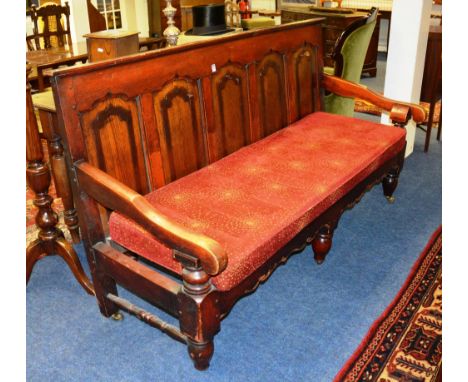 A late 19th / early 20th century stained wood hall bench, with carved panelled back rest, shaped arm rests, ending in short s
