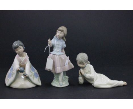 A Nao figure of a standing girl, along with two other Nao figures 