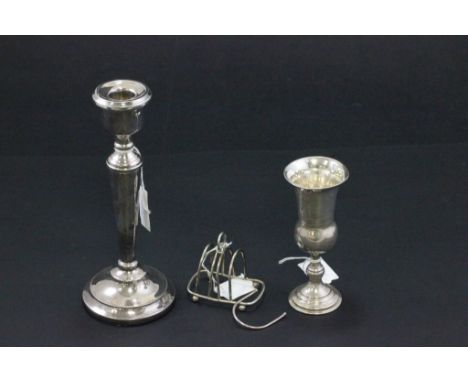 A silver weighted candlestick, along with a silver toast rack (af) and a silver goblet 