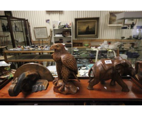 A carved wooden model of a golden eagle perched on a rock , along with a wall bracket in the form of an elephant's head and a