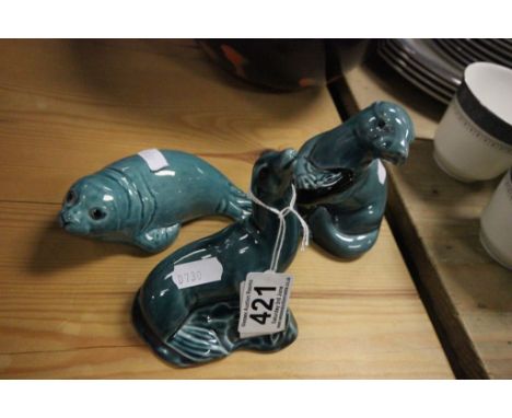 Two  Poole pottery sea lions, along with Poole otter clutching a fish 
