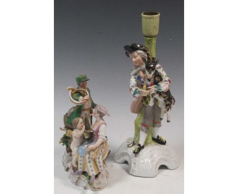 A Stitzendorf figure group of a man with a horn and lady and cherub at his feet; a German porcelain figural candlestick