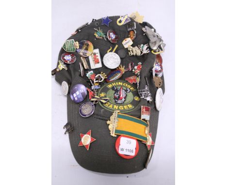 A VINTAGE CAP WITH OVER 60 ASSORTED ENAMEL BADGES