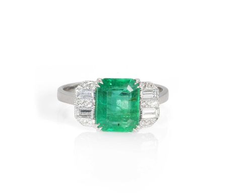 An emerald and diamond ring,  with a step cut emerald, 7.00 x 9.00mm, double claw set to the centre, flanked either side by a