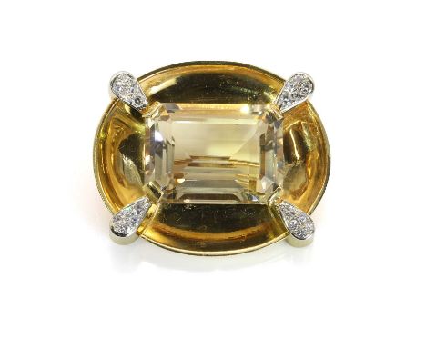A citrine and diamond brooch, the large step cut citrine claw set to the centre of a concave oval plaque, accented with four 