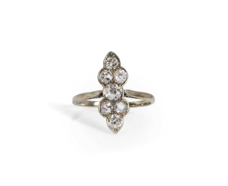 An early 20th century diamond fingerline ring,  with seven old mine cut diamonds bead set in white to a scalloped plaque, to 