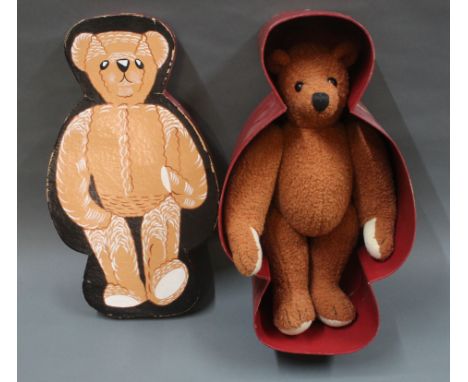 A vintage teddy bear, having plastic black eyes, pointy nose, jointed limbs, and displayed within an illustrated cardboard te