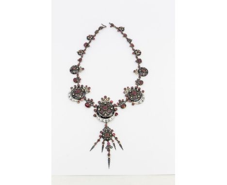 A late 19th century Austro Hungarian enamel and garnet gilt necklace, comprising a graduated necklace of clack enamel open wo