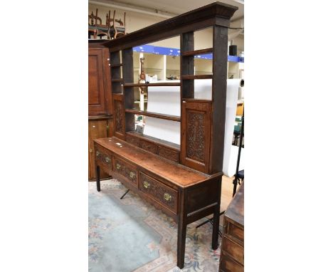 An 18th century solid oak dresser with removable plate rack, three top single drawers, ornate skirt on block legs, later carv