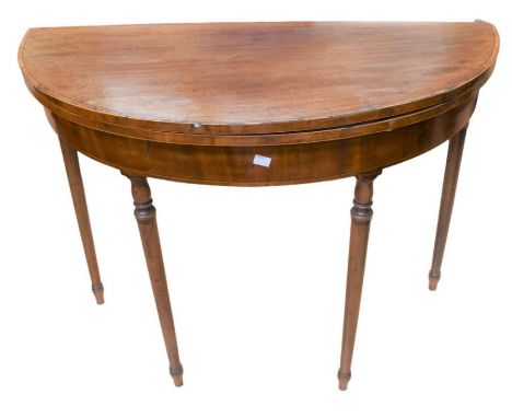 A late George III mahogany demilune card table with a green velvet playing surface with round tapered, turned legs