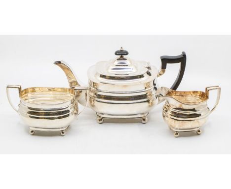 A Georgian style three piece teaset comprising: teapot, sugar bowl and milk jug, on four ball feet, the teapot with ebonised 