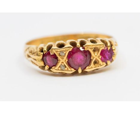 A ruby and diamond 18ct gold ring comprising three graduated round mixed cut rubies with diamond set accents, width approx 7m