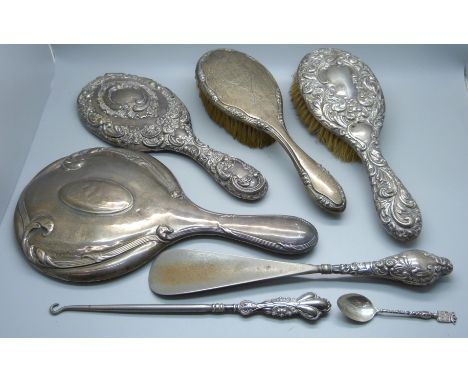 A collection of silver items, two hand mirrors, two brushes, a spoon, and a button hook and shoe horn 