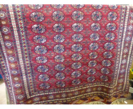 A Vintage Woollen Teke Style Rug, having red background with rows of guls within a central panel, approx 190 cms x 280 cms. 