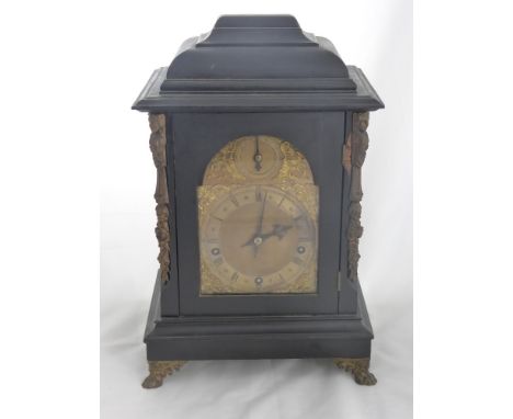 An Antique German Ebonised Bracket Clock, the clock features a brass face with Roman dial and decorative brass mounts to eith