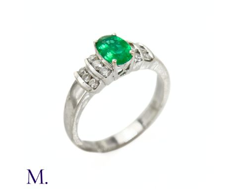 The 18ct white gold ring is set with an oval-cut emerald of approximately 0.40ct, with stepped shoulders set with approximate