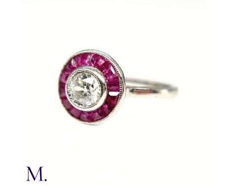 The platinum ring is set with a round cut diamond to the centre of approximately 0.55ct with purple-red calibrated rubies in 