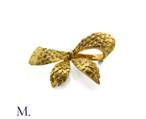 The textured bow brooch by Cartier is fully signed and bears the French control mark for 18ct gold.Weight: 10.8g Size: 43x20m