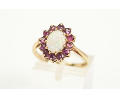 A 9CT GOLD OPAL AND GARNET RING, designed with a central oval opal cabochon with a circular cut garnet surround, 9ct hallmark