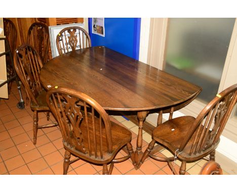 A REPRODUCTION OAK CIRCULAR TOPPED GATE LEG TABLE, open diameter 152cm and six wheel spindle back chairs on a crinoline stret