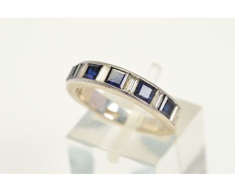 A SAPPHIRE AND DIAMOND HALF ETERNITY RING, designed as a channel set row of slightly graduated square cut sapphires interspac