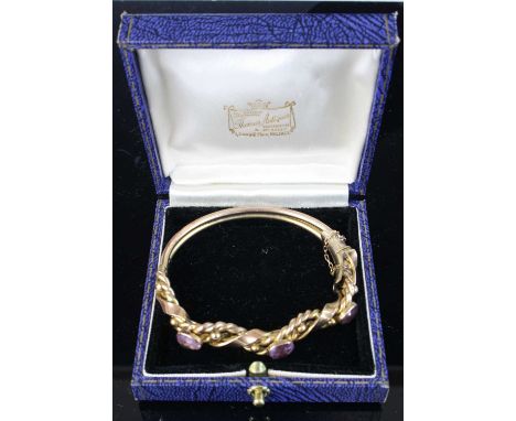 A vintage 9ct gold and amethyst set hinge bangle, arranged as three bezel set amethysts within double rope twist and ribbon b