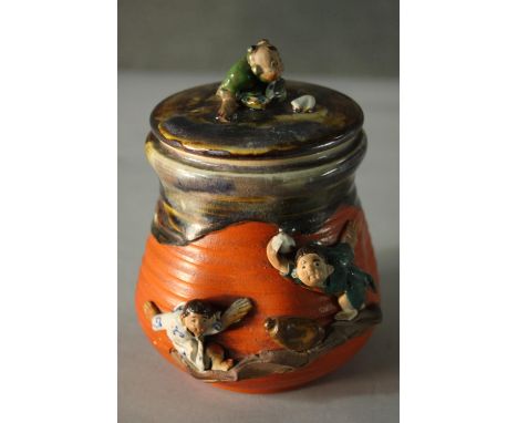 A glazed and hand painted ceramic figural design Japanese lidded jar. Decorated with young children in traditional dress. H.1