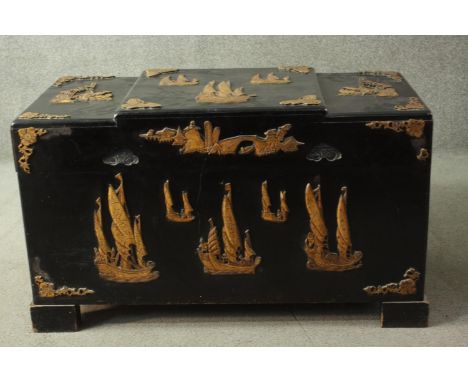 A 20th century Chinese camphorwood trunk, ebonised, carved with sailing boats in relief, with a fitted interior. 
