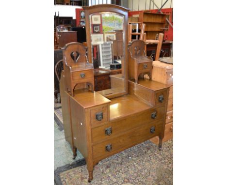 An Art Nouveau oak dressing table, arched mirror flanked by pierced galleries and short drawers to superstructure, two short 