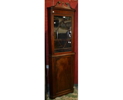 A mahogany floor standing corner cabinet, broken swan neck pediment. gilt metal griffin finial, canted angles, astragal glaze