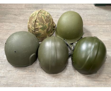 Two US post-war helmets, one with camouflage cover, together with other post-war examples including fireman's