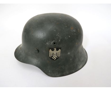 A German M42 pattern helmet with Eagle Crest to left side and red, white and black emblem to right, no visible markings to ri