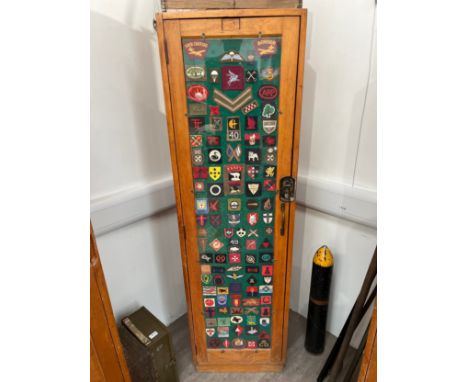 A post-war beech and plywood locker, thought to be RAF Air Ministry, the door with a collection of military badges including 