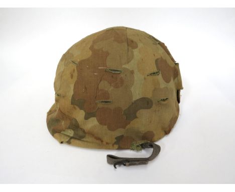 A post-war US Army helmet with liner and camo cover