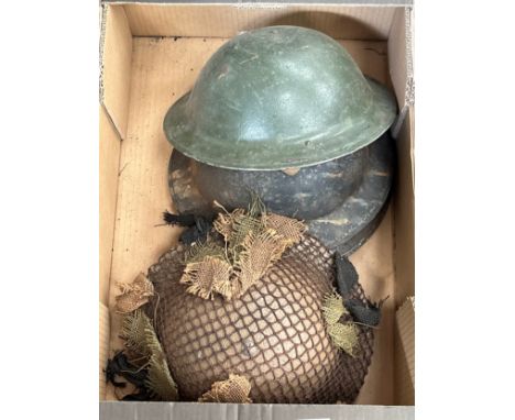 A box containing a Brodie helmet with 1942 dated liner, two further Brodie shells and a post war Brodie helmet with camouflag