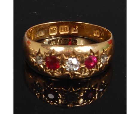 An 18ct gold ruby and diamond dress ring, arranged as three old cut diamonds in a star engraved setting, dispersed with twin 