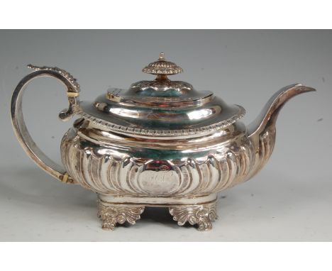 A late Georgian silver teapot, of half-reeded and fluted oval bombe form, having finial topped hinge cover, on lion paw cast 