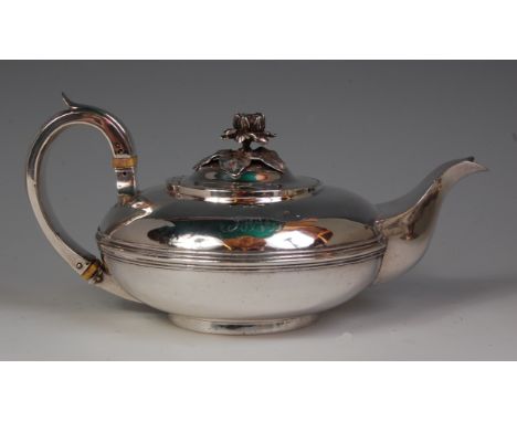A George IV silver teapot, of squat circular form, having a leaf and flower head cast hinged cover, the C scroll handle with 