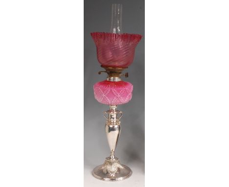 A late Victorian silver plated pedestal oil lamp, having folded glass cranberry shade and moulded pink glass reservoir, h.59c