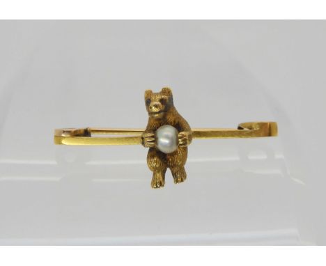 A 15ct gold brooch of a bear holding a pearl, length 3.2cm x 1.4cm, weight 3.8gms Condition Report:Available upon request