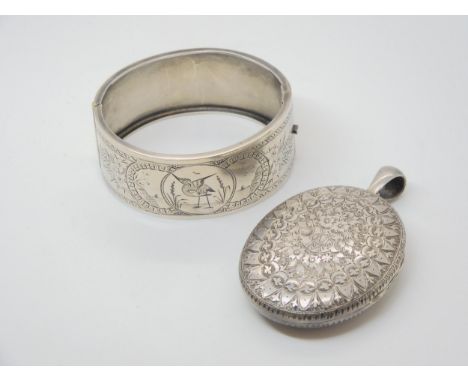 A silver bangle engraved with a bird, and a white metal Victorian heavily engraved locket Condition Report:Not available for 