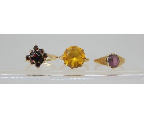 A 9ct garnet cluster ring, size N, a 9ct purple gem ring, size K1/2, and a yellow metal ring set with a yellow gem, size L1/2