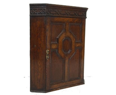 A 19th century oak hanging corner cabinet. Of oak construction with qtr panel door having central cartouche under carved dent