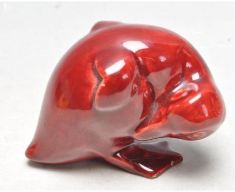 An unusual early 20th century ceramic deep ox blood red flambe glazed figurine of a crouching chick. Of Royal Doulton, Bernar