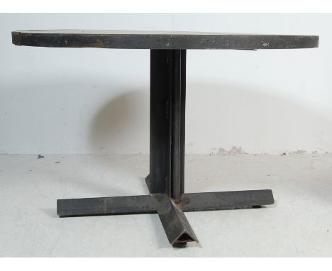 A vintage style factory industrial handmade refectory metal steel frame dining table of a circular form having rustic wooden 