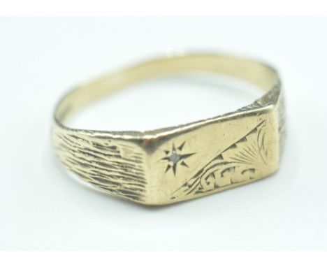 A hallmarked 9ct gold signet ring having a rectangular panel head with engraved star and foliate design with bark effect shou