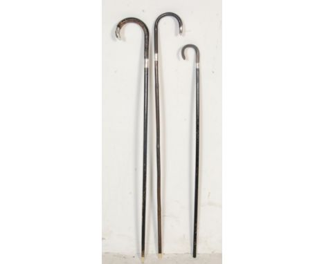 A collection of three early 20th century antique walking sticks / canes comprising of a bone handled cane with a silver colla