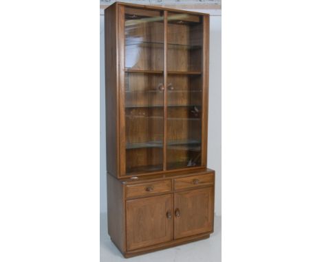 Ercol - Lucian Ercolani - A vintage late 20th century elm bookcase cabinet vitrine having twin glazed doors opening to reveal